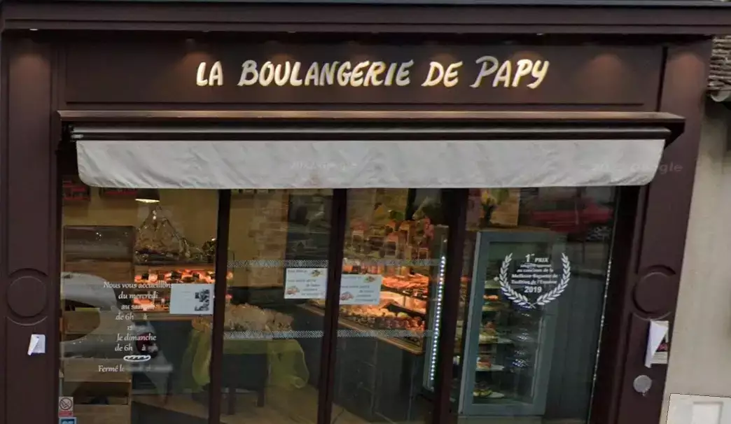 Odisourd-ou-manger Façade d’une boulangerie traditionnelle appelée ‘La Boulangerie de Papy’, avec une enseigne écrite en lettres dorées. La vitrine montre des pâtisseries et des pains exposés à l’intérieur. Des horaires d’ouverture sont visibles sur la porte, et un autocollant mentionnant une distinction obtenue en 2019 est apposé sur la vitre. L’ensemble donne une ambiance chaleureuse et artisanale.